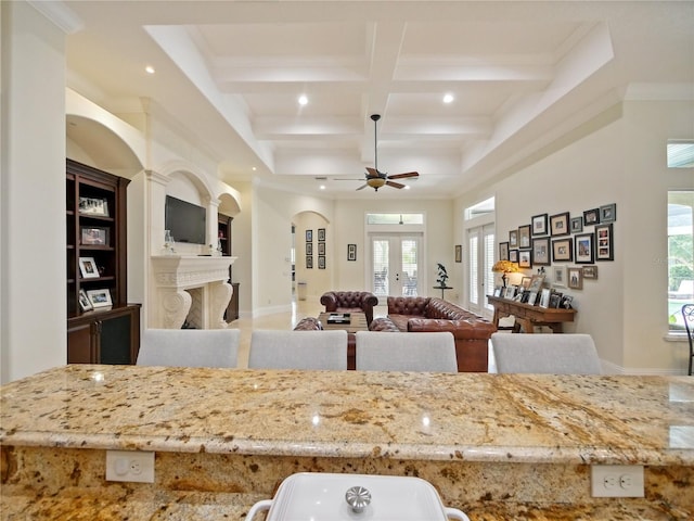 kitchen featuring french doors, a fireplace, coffered ceiling, ceiling fan, and beamed ceiling