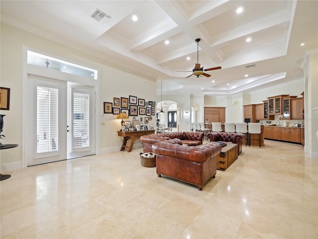 living room with ceiling fan, coffered ceiling, beamed ceiling, crown molding, and a towering ceiling