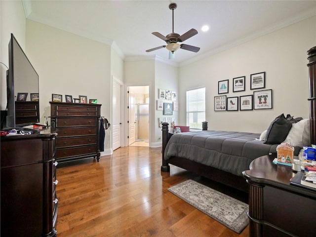 bedroom featuring ensuite bath, ceiling fan, wood-type flooring, and ornamental molding