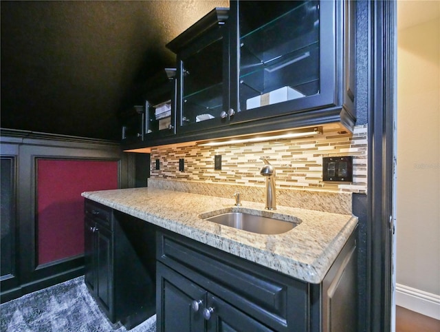 kitchen featuring decorative backsplash, light stone counters, and sink