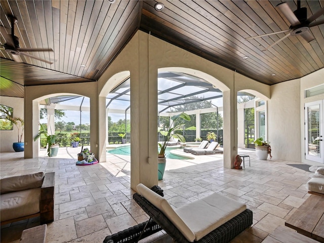 view of patio / terrace featuring glass enclosure and a swimming pool with hot tub