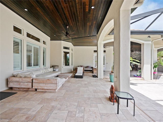 view of patio with glass enclosure, ceiling fan, and an outdoor living space