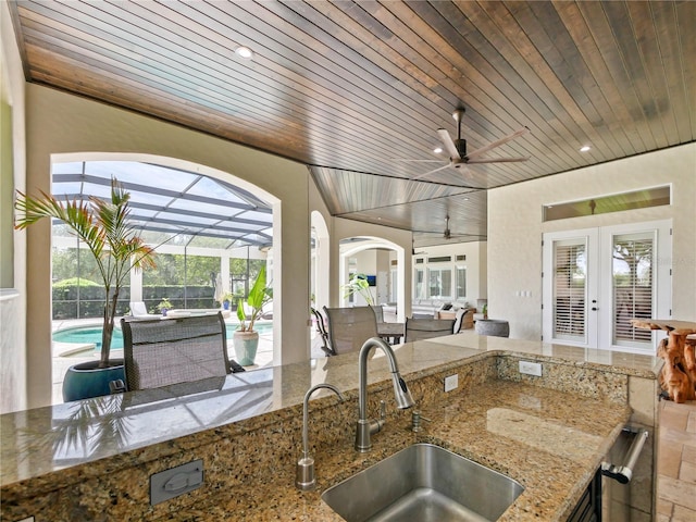 view of patio / terrace with glass enclosure, ceiling fan, an outdoor wet bar, and french doors