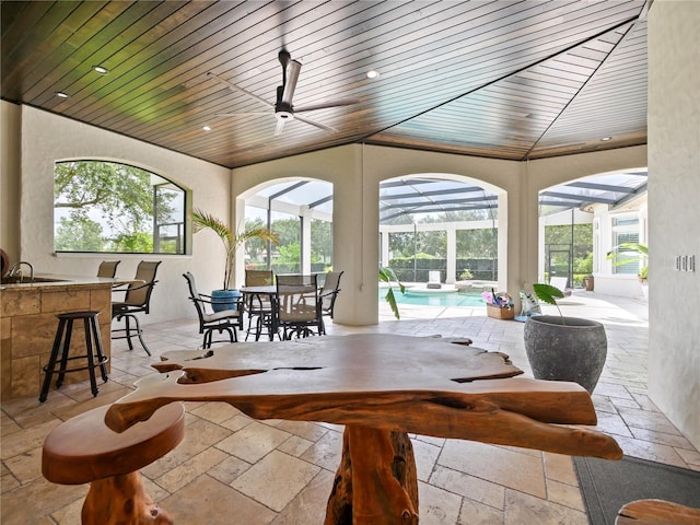 sunroom / solarium with ceiling fan, a swimming pool, and wood ceiling