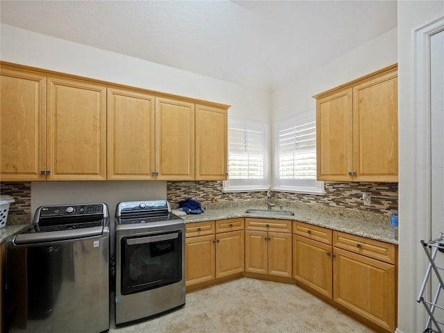 clothes washing area with cabinets, sink, and washing machine and clothes dryer