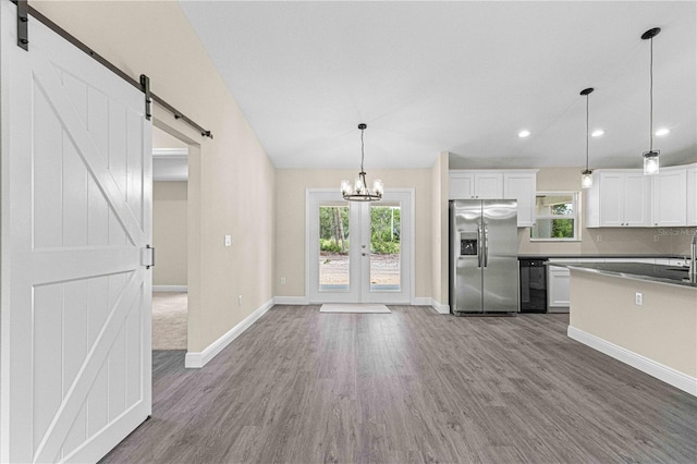 kitchen featuring a barn door, white cabinets, pendant lighting, dark wood-type flooring, and stainless steel fridge