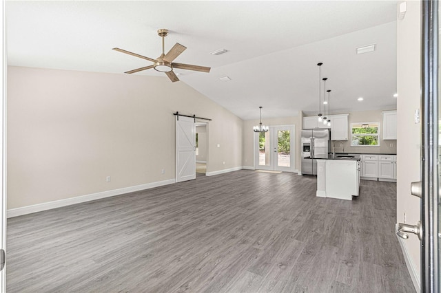 unfurnished living room featuring ceiling fan, sink, hardwood / wood-style flooring, a barn door, and lofted ceiling