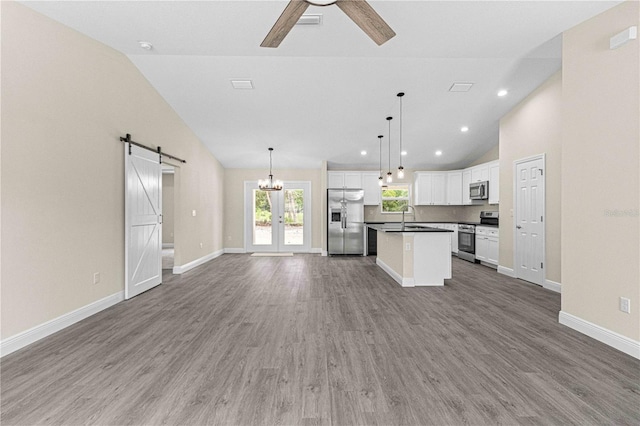 kitchen featuring a center island, decorative light fixtures, white cabinetry, stainless steel appliances, and a barn door