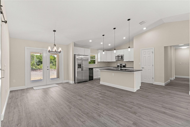 kitchen featuring appliances with stainless steel finishes, decorative light fixtures, white cabinetry, wood-type flooring, and a kitchen island with sink