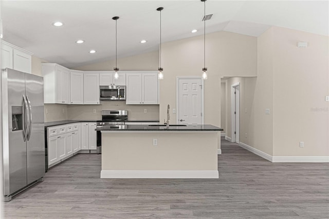 kitchen featuring white cabinetry, hanging light fixtures, appliances with stainless steel finishes, and a center island with sink