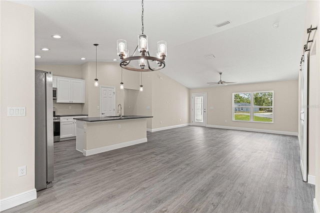 kitchen featuring pendant lighting, vaulted ceiling, hardwood / wood-style flooring, white cabinetry, and an island with sink