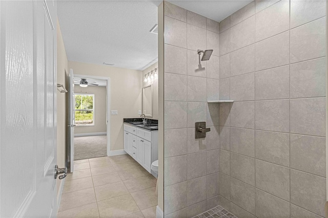 bathroom with tile patterned floors, toilet, vanity, and tiled shower