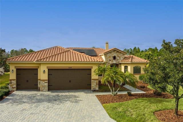 mediterranean / spanish-style house with a garage and solar panels