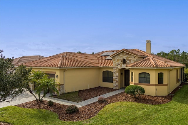 mediterranean / spanish house with a garage, a front lawn, and solar panels