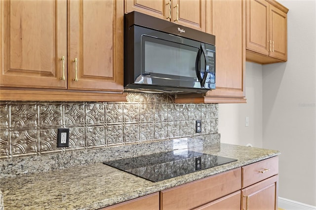 kitchen with backsplash, light stone counters, and black appliances