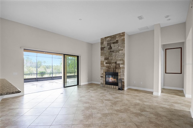 unfurnished living room featuring light tile patterned flooring and a stone fireplace