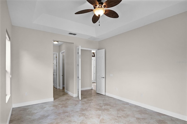 unfurnished bedroom featuring ceiling fan and a tray ceiling