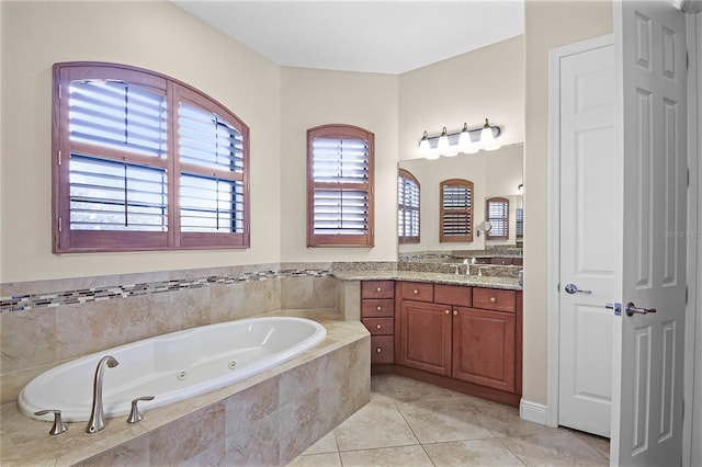 bathroom featuring tile patterned floors, tiled tub, vanity, and a wealth of natural light