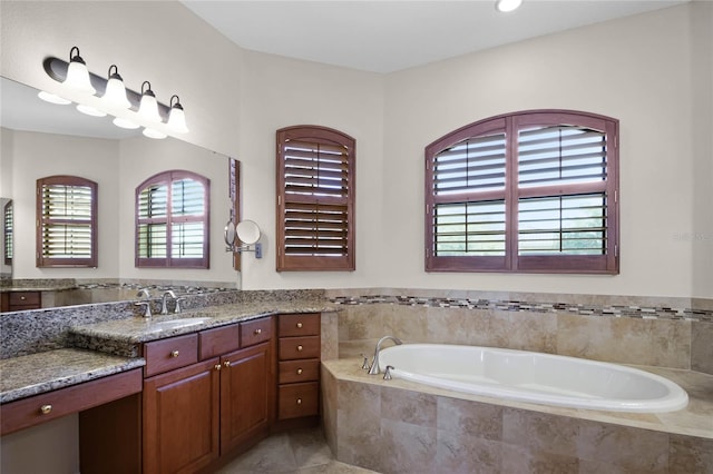 bathroom with a relaxing tiled tub, vanity, and tile patterned flooring