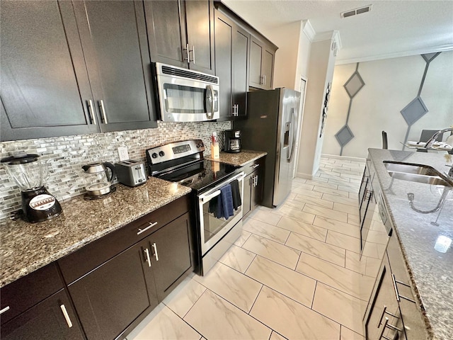 kitchen with appliances with stainless steel finishes, sink, dark brown cabinetry, decorative backsplash, and crown molding