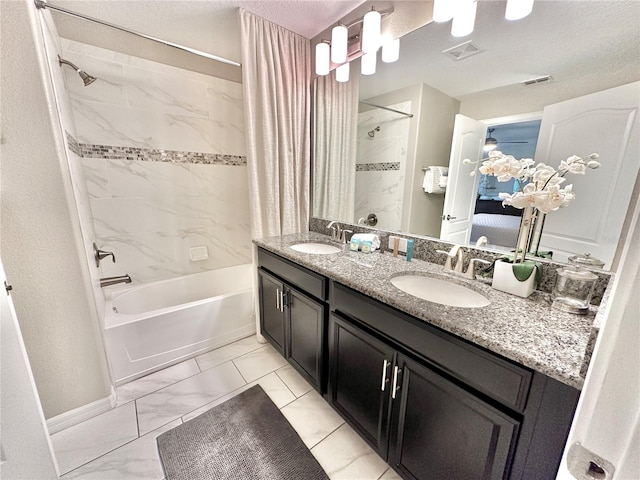 bathroom featuring dual vanity, tile patterned flooring, tiled shower / bath combo, and a textured ceiling