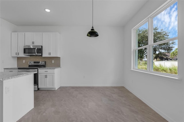 kitchen with light stone countertops, hanging light fixtures, stainless steel appliances, and white cabinetry