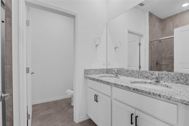 bathroom with vanity, toilet, and a tile shower