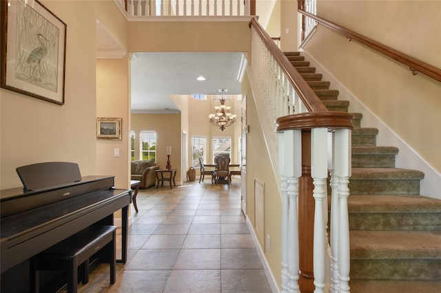 interior space featuring a towering ceiling, ornamental molding, and a notable chandelier