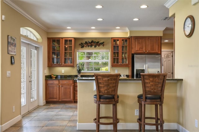 kitchen featuring stainless steel fridge with ice dispenser, plenty of natural light, and a kitchen bar