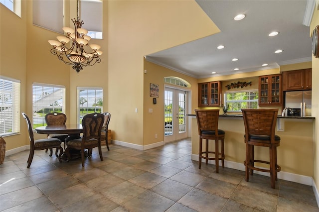 kitchen featuring a breakfast bar area, ornamental molding, a notable chandelier, stainless steel fridge with ice dispenser, and french doors