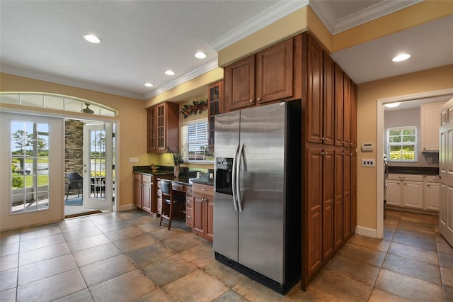 kitchen featuring stainless steel refrigerator with ice dispenser, ornamental molding, and built in desk