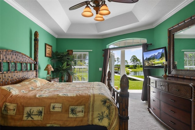 bedroom featuring light carpet, a tray ceiling, crown molding, and ceiling fan