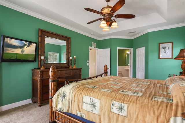 bedroom featuring connected bathroom, ornamental molding, a raised ceiling, carpet floors, and ceiling fan