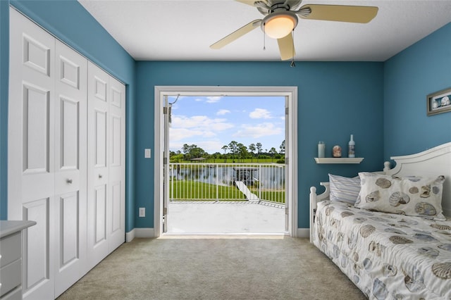 carpeted bedroom with a water view, ceiling fan, a closet, and access to outside