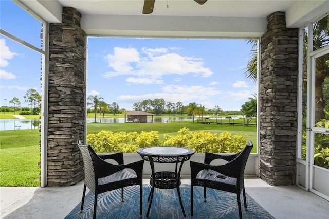 sunroom with ceiling fan and a water view