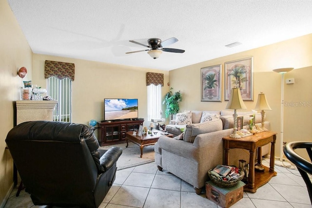 living room with ceiling fan, a textured ceiling, and light tile patterned floors