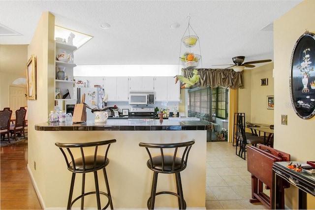 kitchen featuring stainless steel appliances, white cabinetry, a breakfast bar area, and kitchen peninsula