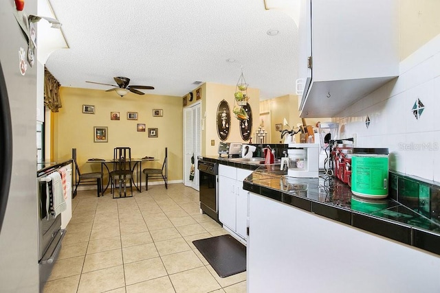 kitchen with light tile patterned flooring, white cabinetry, a textured ceiling, black dishwasher, and ceiling fan