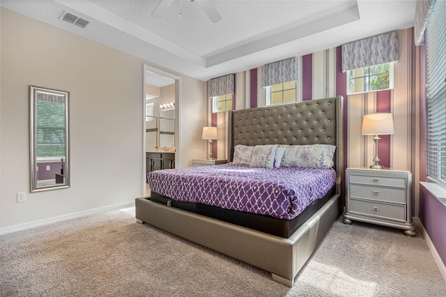 carpeted bedroom featuring ceiling fan, a tray ceiling, and connected bathroom