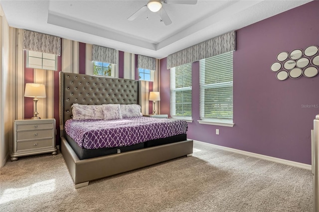 bedroom with carpet flooring, ceiling fan, and a raised ceiling