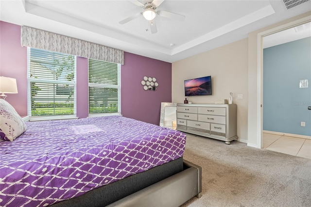 bedroom with a tray ceiling, light carpet, and ceiling fan