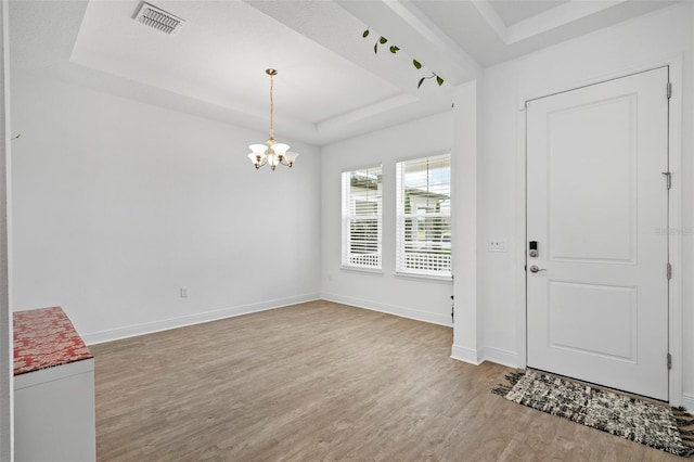 entrance foyer with light wood-type flooring, a chandelier, and a raised ceiling