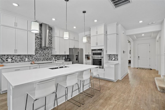 kitchen featuring wall chimney exhaust hood, white cabinets, and stainless steel appliances