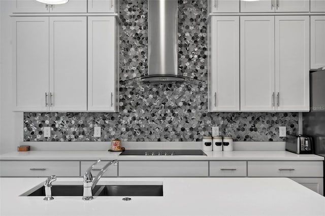 kitchen featuring white cabinets, wall chimney range hood, and black electric stovetop