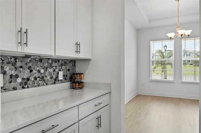 bar featuring hanging light fixtures, white cabinets, a chandelier, and tasteful backsplash