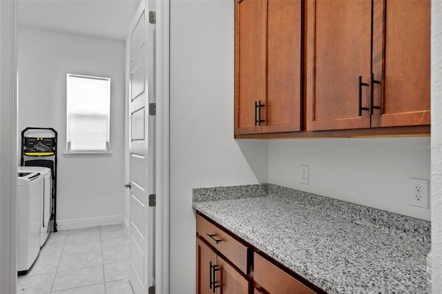 kitchen with light stone counters, light tile patterned floors, and washer and dryer