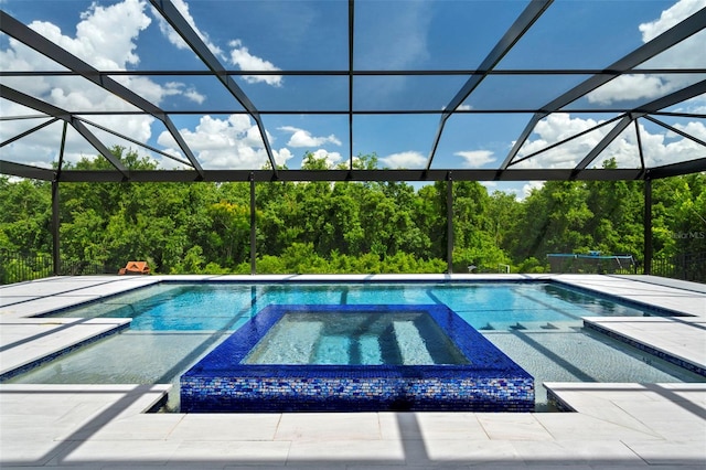 view of pool featuring glass enclosure, an in ground hot tub, and a patio