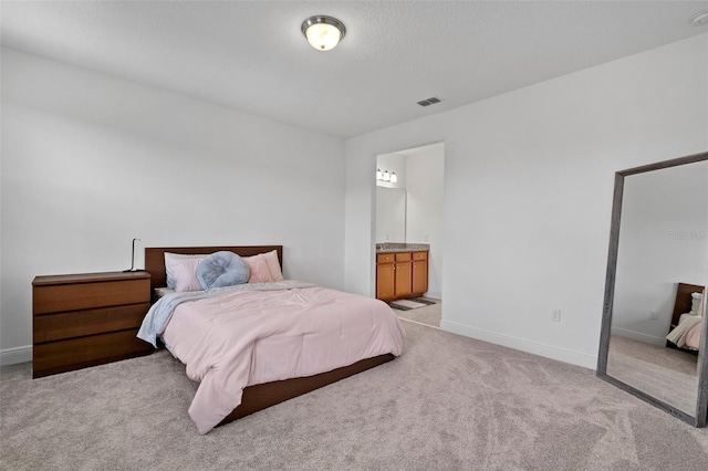 bedroom featuring ensuite bathroom and light carpet