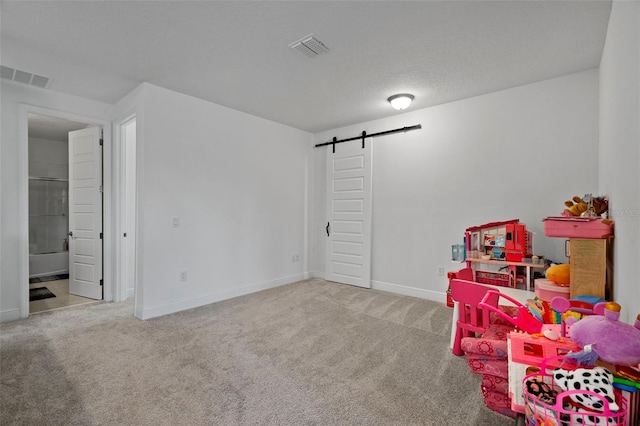 playroom featuring light carpet and a barn door