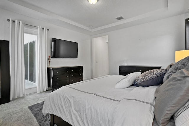 carpeted bedroom featuring a textured ceiling and a tray ceiling